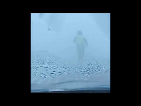 Полицейский бежит по заметённой трассе, показывая дорогу в Костанайской области