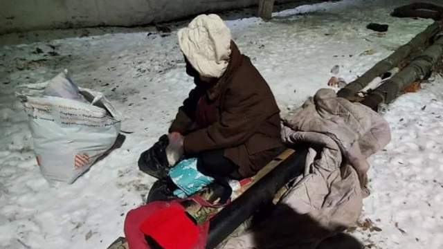 Бездомная женщина замерзает на трубах в Рудном